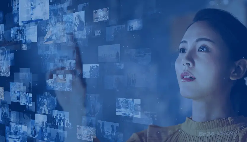 Mulher tocando em uma tela virtual com várias imagens projetadas, demonstrando o processo interação e comunicação obtidos pela transformação digital.