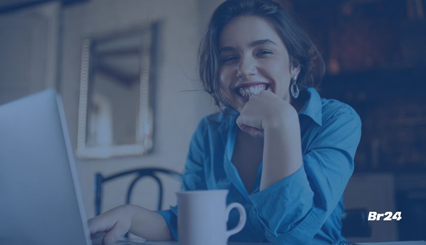 Mulher branca sorrindo em frente a um notebook enquanto se comunica com eficiência com seus colegas de trabalho no chat corporativo.