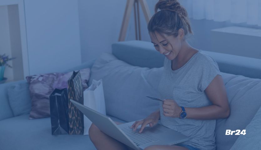 Mulher sorrindo usando notebook e inserindo dados do seu cartão de crédito no sistema de pagamento online da empresa onde está fazendo uma compra.
